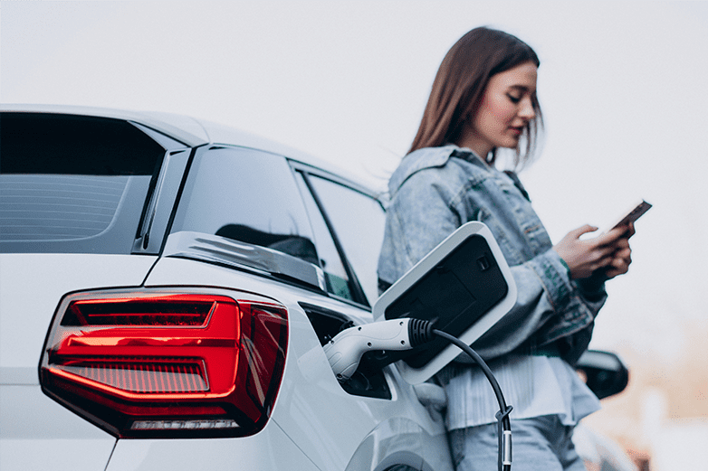 Mujer cargando el coche eléctrico con cargador portátil