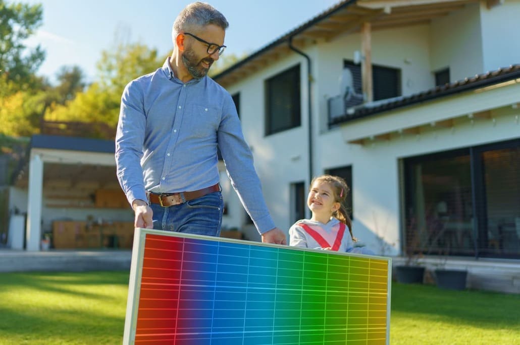 padre e hija llevan transportan un panel solar con los colores del logo de TotalEnergies