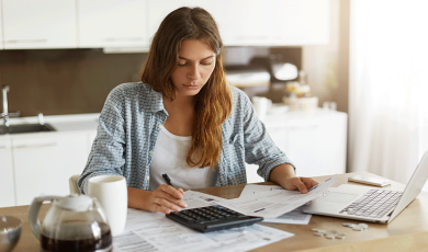 Mujer analizando sus facturas eléctricas con calculadora y el ordenador