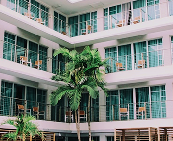 fachada de un hotel con terrazas y dos palmeras en la parte baja
