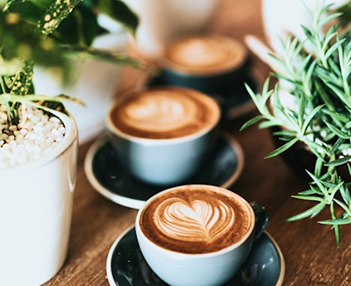 tres caf&eacute;s reci&eacute;n hechos colocados encima de una mesa de madera