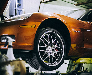 coche naranja suspendido en el foso de un taller