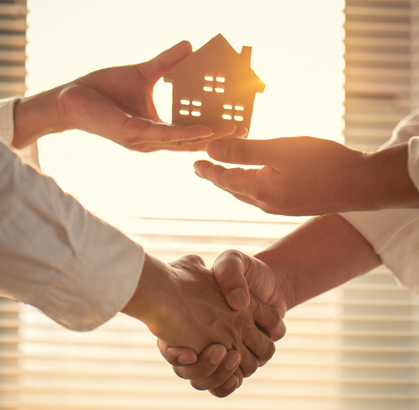 dos personas se dan la mano e intercambian una figura de una casa