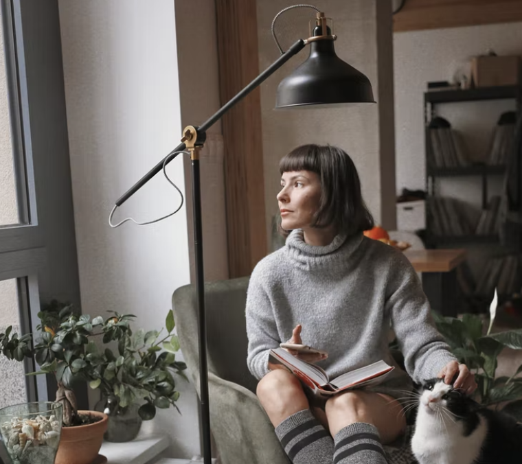 mujer leyendo un libro y acariciando a un gato